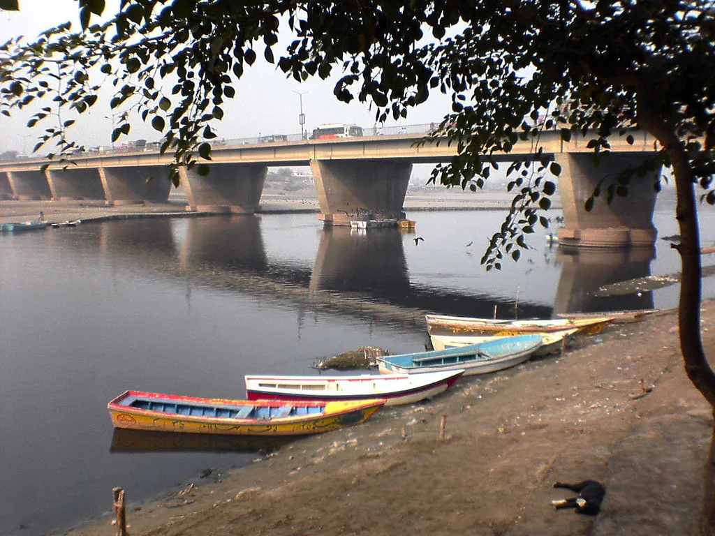 Painted rowing boats moored on the River Ravi beside a Lahore bridge